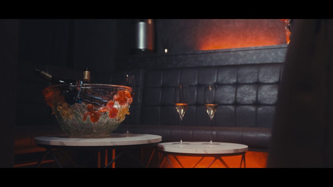 Champagne bucket with ice and glasses set on lounge table.