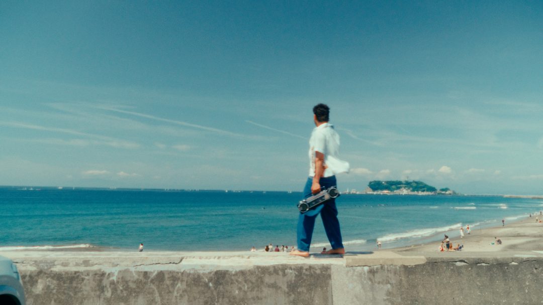 Man standing on seaside wall looking at ocean horizon.
