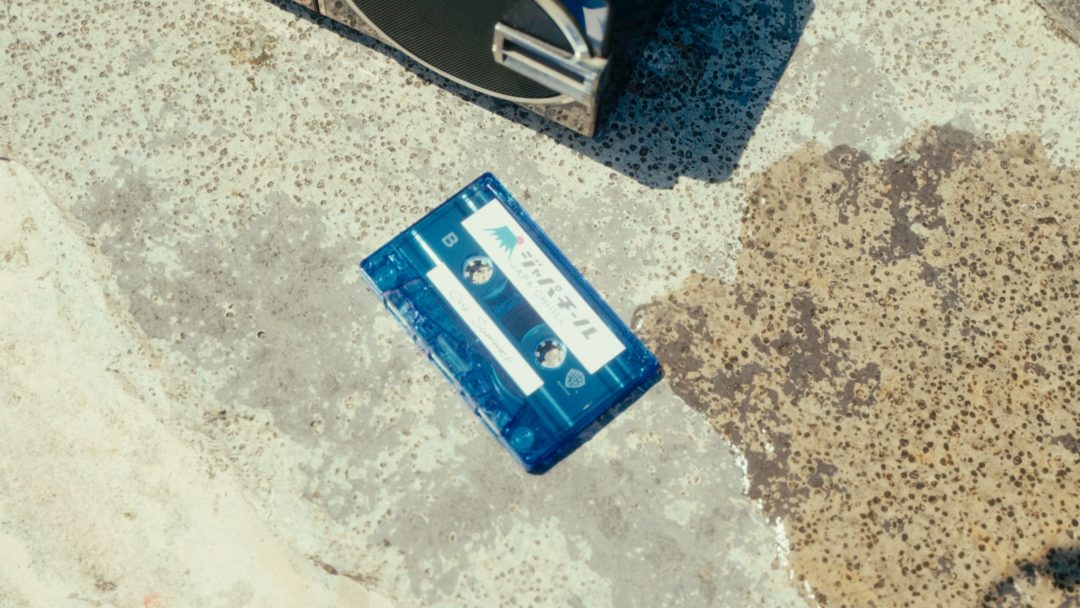Blue cassette tape lying on concrete near boombox.