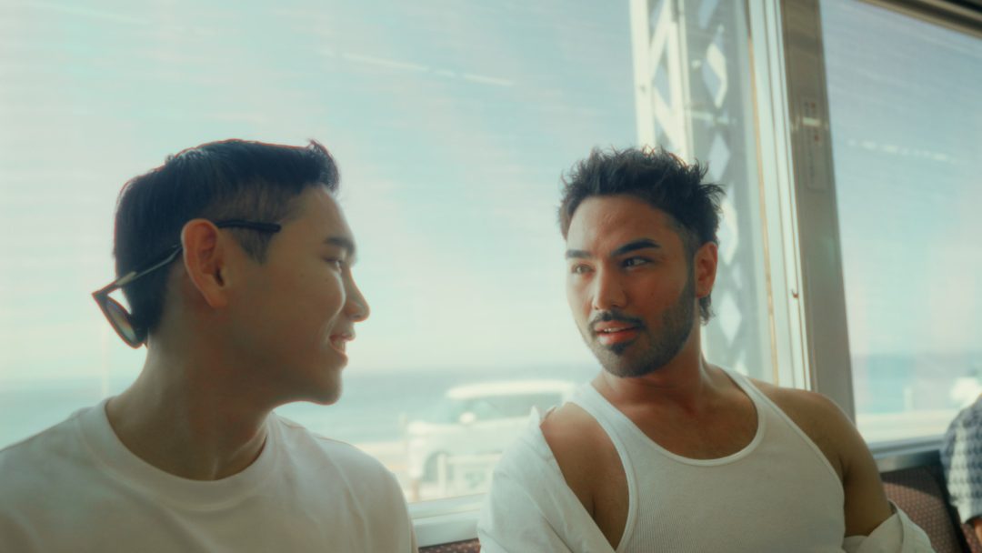 Two men talking together while riding on a train.