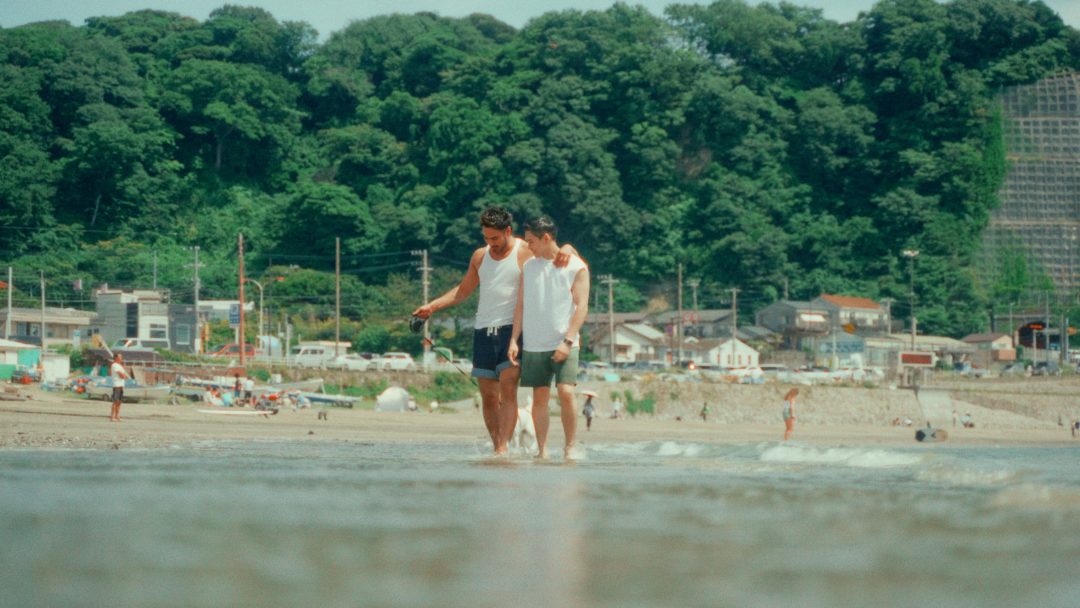 Group of men walking barefoot along the shoreline at the beach.