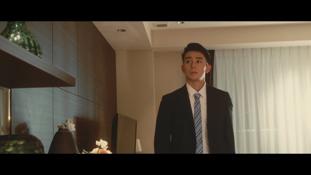 Young man in suit standing in modern apartment.