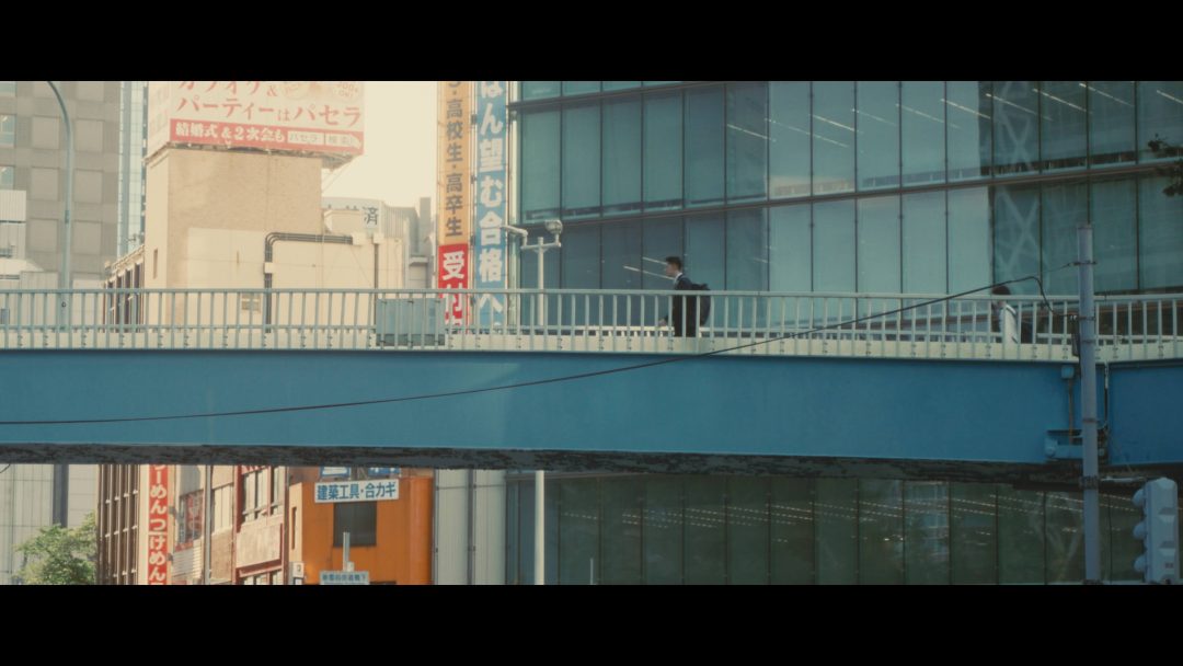 Person walking alone on blue pedestrian bridge in Tokyo.