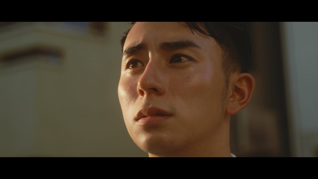 Close-up of young man’s face with serious expression outdoors.