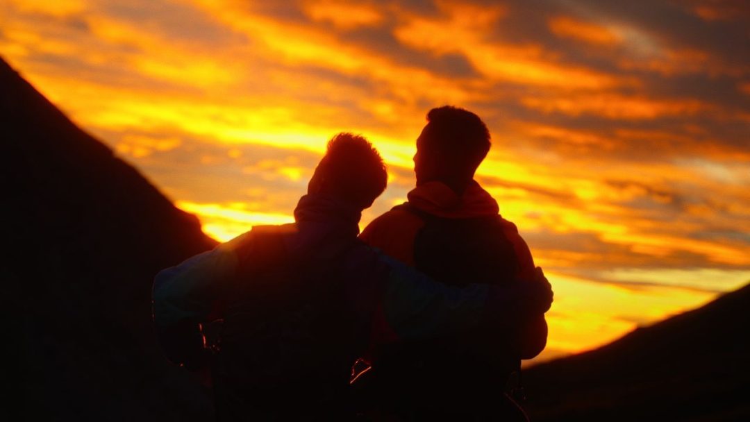 two person watching the sunset in the mountains in japan, sky is dreamy orange pink